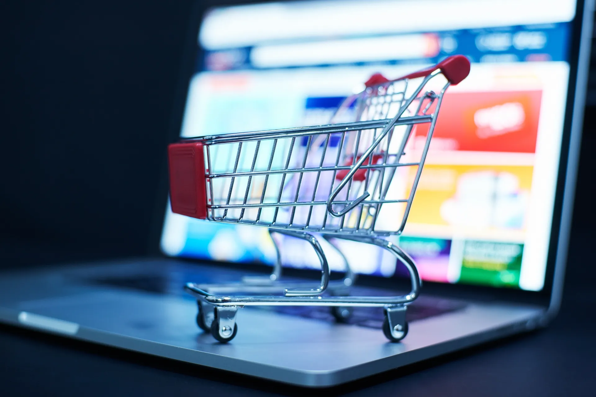 Miniatur-Einkaufswagen auf der Laptop-Tastatur symbolisiert Online-Einzelhandel und E-Commerce